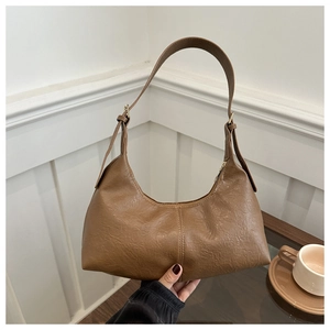 Détail d'un sac bandoulière marron en forme de croissant avec texture cuir vintage et zip