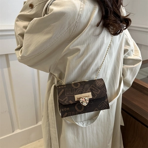 Vintage brown monogram chain bag with heart clasp worn with a beige trench coat