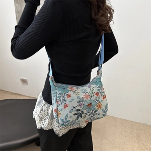 Floral jacquard crescent moon bag with adjustable strap worn by model in a side view