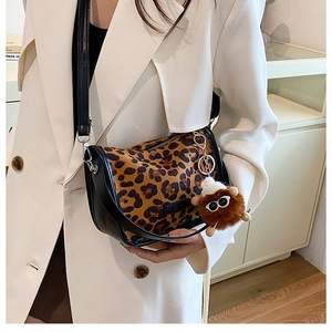 Detail of leopard print handbag with black leather trim and plush monster charm