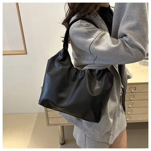 Side view of black pleated cloud shoulder bag with soft leather texture and chic vintage design