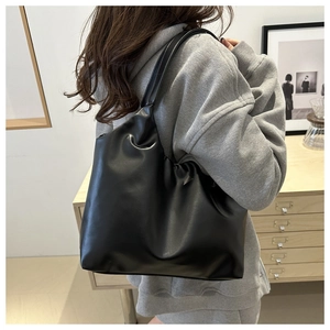 Close-up of black ruched cloud tote bag made of soft PU leather shown on a model shoulder