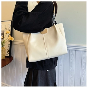 Detailed view of flexible creamy white leather tote with chain strap and side pleats