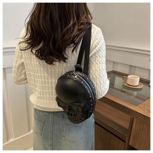 Détail d'un sac bandoulière tête de mort noir avec rivets argentés porté par le modèle