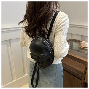 Détail d'un mini sac à dos gothique noir avec relief tête de mort 3D et clous argentés