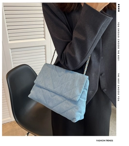 Μοντέλο με γαλάζια τσάντα ώμου denim με ραφή V και διακοσμητική αλυσίδα στο λουράκι