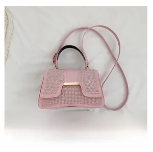 Detail der rosa Strass-Handtasche mit gewölbtem Boden und Gurt auf weißem Stoff