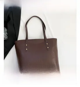 Detail of deep brown crocodile pattern tote bag with gold rivets and smooth PU texture