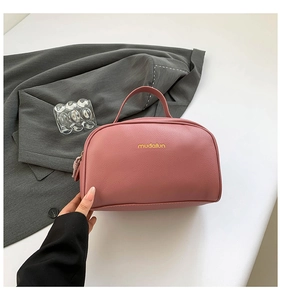 Detail showing high-quality leather texture and branding on the pink makeup bag