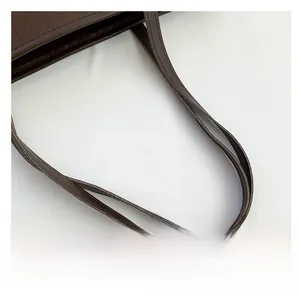 Close-up of dual handles on large tote bag featuring brown crocodile pattern texture