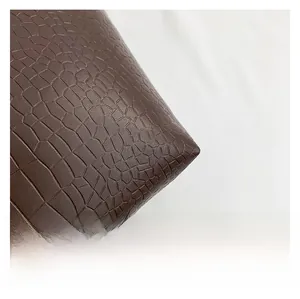 Detailed macro view of deep brown crocodile texture on synthetic leather handbag