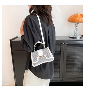 Detail einer modernen weißen Handtasche mit Laserschnitt-Design und Goldmetallschnalle