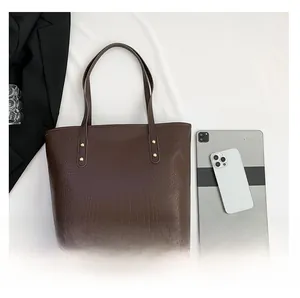Flat lay of brown crocodile texture tote bag with tablet and phone for size comparison
