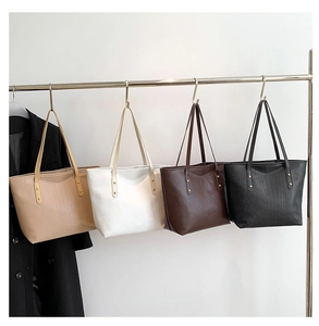 Detail showing four colors of embossed leather tote bags with gold hardware and studs