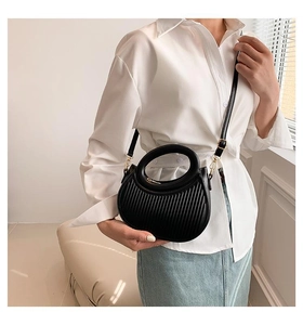 Detail of black pleated half-moon bag with gold metal clips and rounded top handle