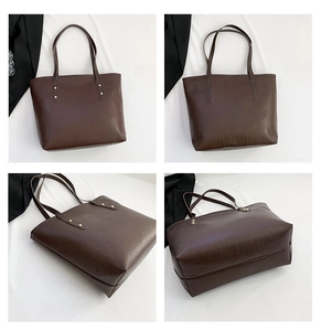 Detail view of large dark brown tote bag with crocodile pattern and golden rivet reinforcement