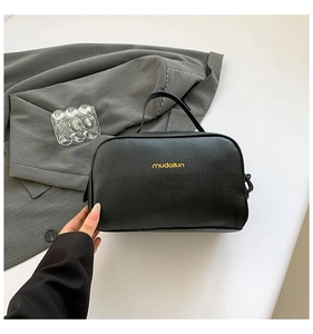 Close-up of black lychee grain PU leather makeup bag with yellow mudailun logo detail