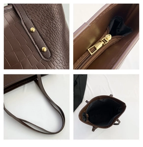 Detail view of large brown crocodile embossed leather tote with zipper and gold rivets