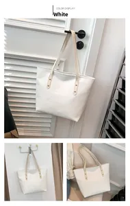 Detail of white crocodile embossed tote bag with gold rivets and long shoulder strap