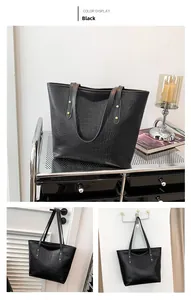 Detail of black faux crocodile leather tote bag with gold rivets and sturdy top handles
