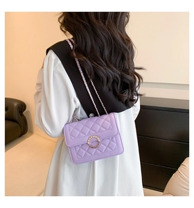 Sac bandoulière lilas matelassé avec boucle en perles porté par un mannequin en intérieur