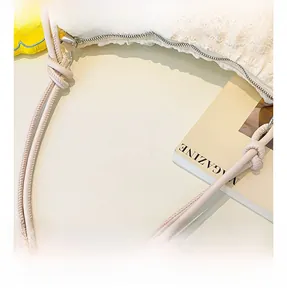 Detail of the knotted cylindrical handle and metal zipper on the apricot soft bag