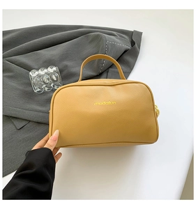 Detail of yellow lychee grain PU leather makeup bag held by hand with logo texture