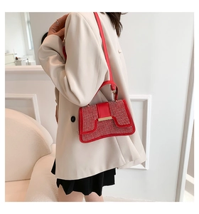 Detailaufnahme der roten Strass-Tasche mit Goldschnalle und beigem Mode-Outfit