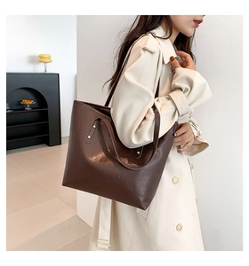 Detail of coffee brown tote bag featuring crocodile texture and metallic rivet accents
