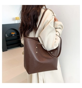 Side view of large brown crocodile pattern tote bag shown worn on shoulder for commuting