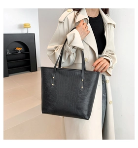 Close-up of black crocodile pattern tote bag featuring gold rivet detail and large capacity