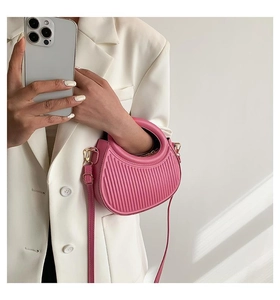Macro shot of pink crescent bag with vertical pleated texture and golden hardware accents