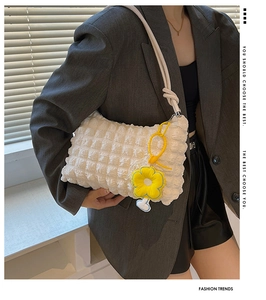 Close-up of white popcorn textured shoulder bag with a yellow flower charm detail