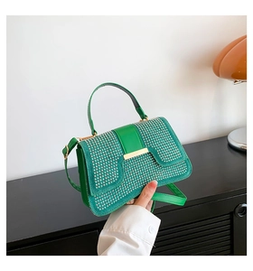 Detailaufnahme der grünen Handtasche mit Silbernieten und goldenem Schnallenverschluss