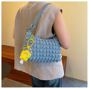 Detailed view of light blue bubble textured shoulder bag with yellow sunflower charm