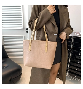 Detail view of beige crocodile embossed tote bag featuring fine texture and gold rivets