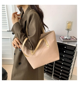 Detail of light beige tote bag with crocodile texture and leather shoulder straps