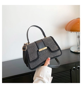 Details der schwarzen Handtasche mit silbernen Nieten und goldener Metallschnalle auf Regal