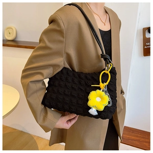 Detail of black underarm bag with bubble texture and yellow sunflower plush charm