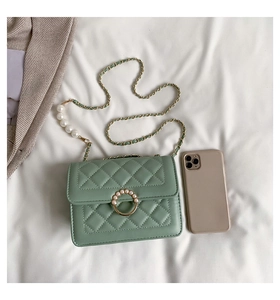 Détail d'un mini sac matelassé vert clair avec fermoir perle et bandoulière chaîne