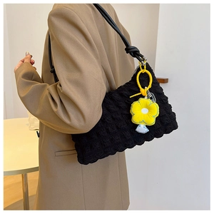Close-up of black bubble textured crossbody bag with a bright yellow floral pendant