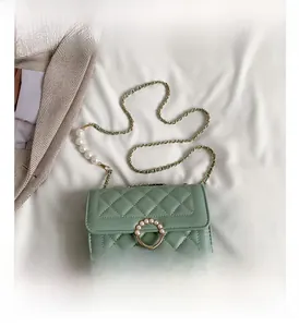 Détail du sac à bandoulière matelassé vert clair avec boucle perle et chaîne en métal