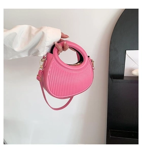 Detail of pink crescent handbag featuring unique vertical pleated texture and gold zippers