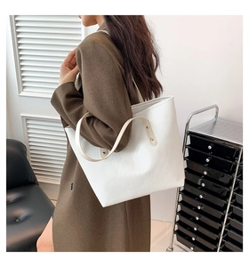 Close-up of white tote bag with crocodile texture and long shoulder straps for women