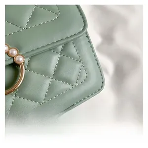 Gros plan sur un sac matelassé vert menthe avec anneau doré et détails en perles blanches