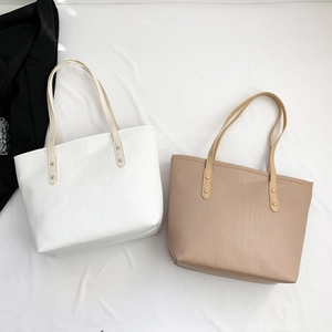 Close-up of white and brown crocodile embossed tote bags with thin shoulder straps