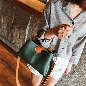 Minimalistische Beuteltasche aus dunkelgrünem Leder mit braunen Kontrastriemen