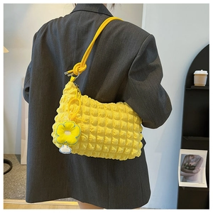 Detail of yellow puffy texture shoulder bag with woven strap and flower pendant