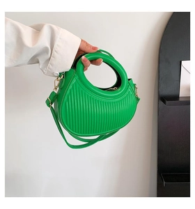 Detail of green crescent handbag with pleated texture and round hollow handle for women