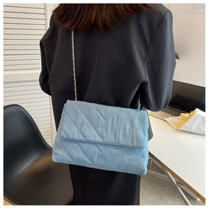 Gros plan d'un sac bandoulière en jean matelassé bleu clair avec chaîne dorée sur mannequin